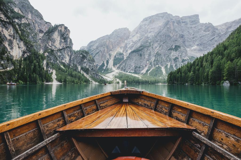 person in boat on lake with mountains
